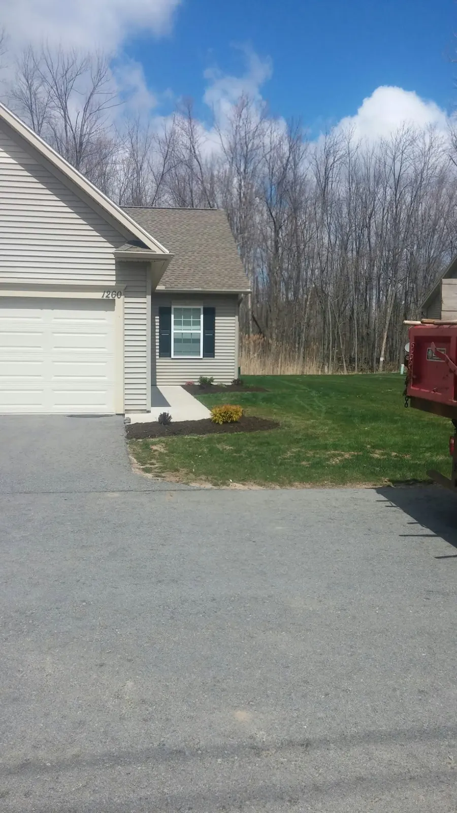 Edged garden bed with fresh mulch along a garage wall in Webster, NY