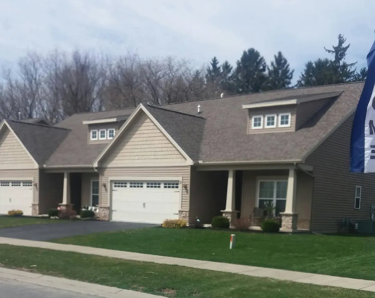 Freshly mowed front lawn in front of a tan two-story home in Webster, NY