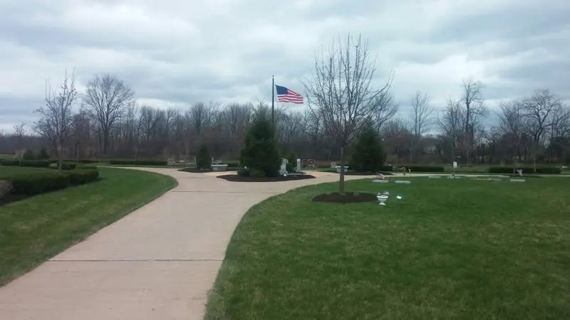 Mowed lawn along a curved paved path with shrubs in the Rochester, NY area