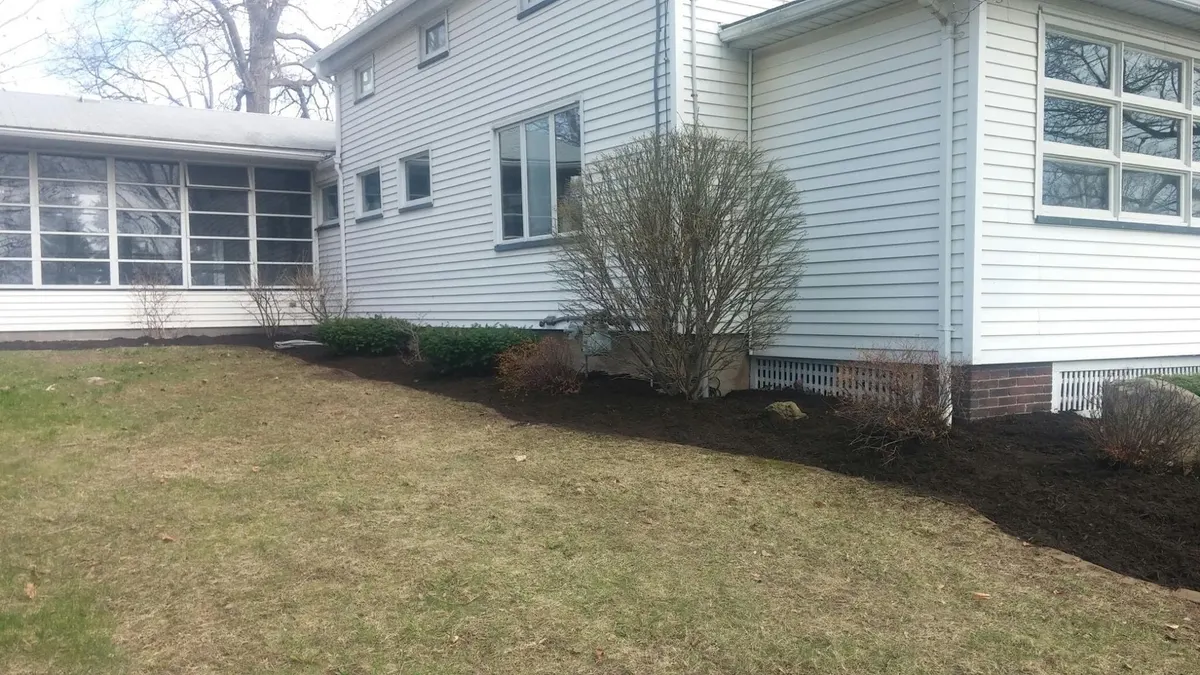 Mowed side yard with garden beds beside a home in Webster, NY