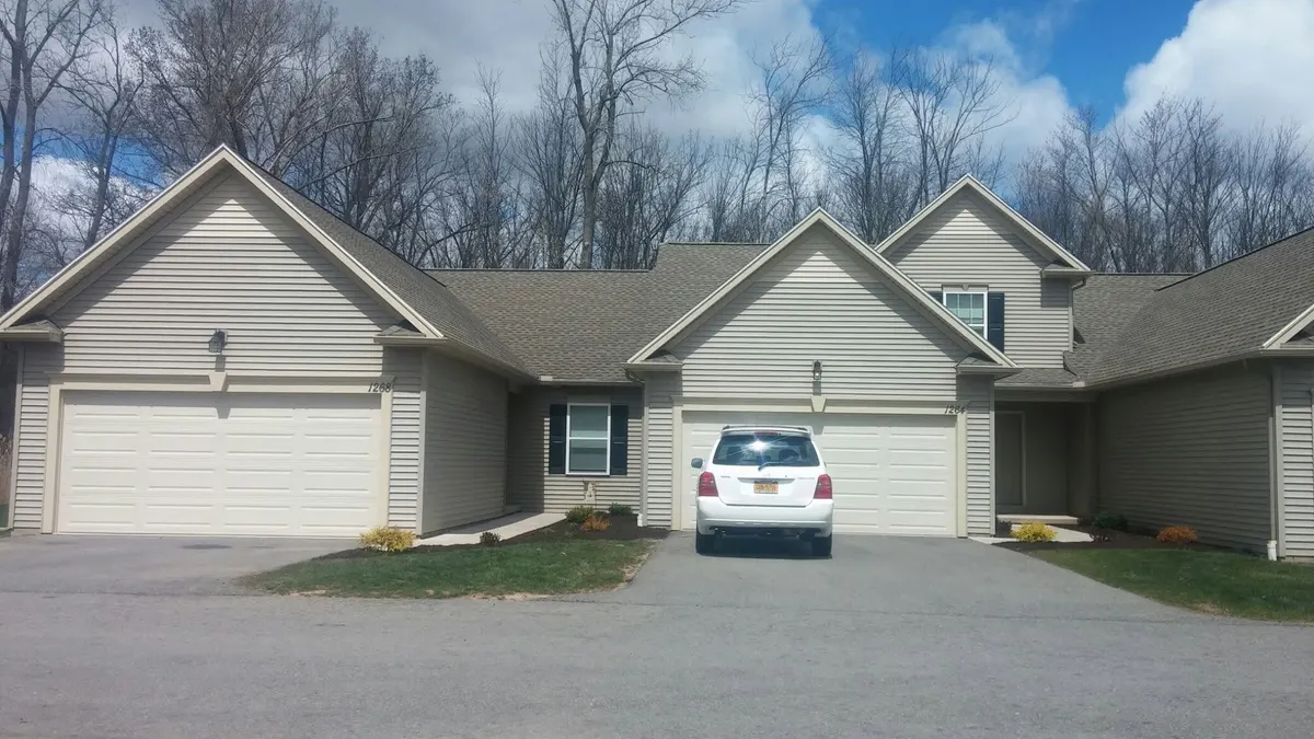 Mowed lawn and driveway of a single-story home with attached garage in Webster, NY