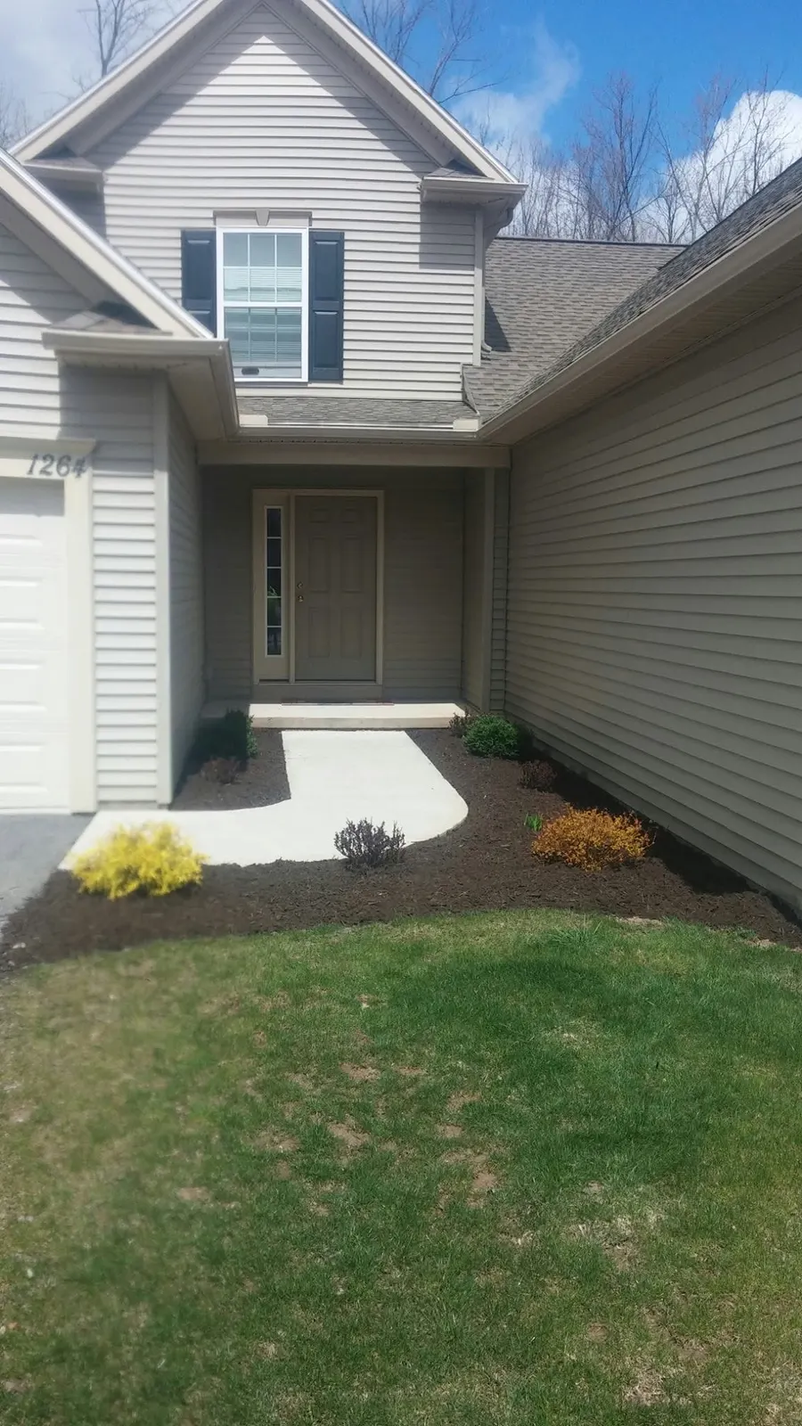 Freshly edged garden beds with dark mulch beside a front entry after a spring clean-up
