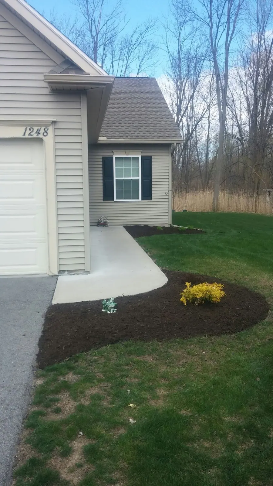Crisp edged garden bed with fresh dark mulch beside a garage after a spring clean-up in Webster, NY